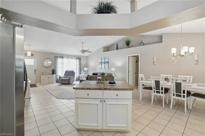 Kitchen featuring freestanding refrigerator, light tile patterned floors, white cabinetry, ceiling fan, and dark countertops