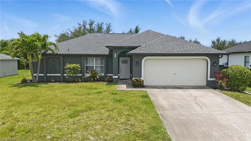 Ranch-style house with stucco siding, an attached garage, a front yard, and a shingled roof