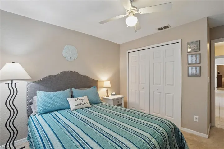 Bedroom with a closet, light colored carpet, ceiling fan, and baseboards