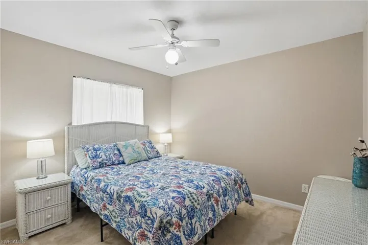 Bedroom with light carpet, baseboards, and a ceiling fan