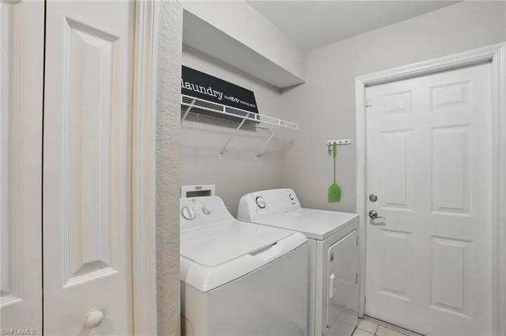 Laundry area with independent washer and dryer and light tile patterned flooring