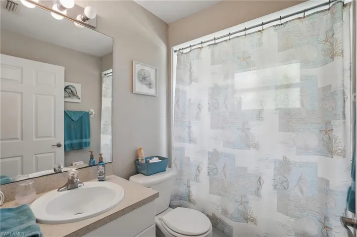 Full bath featuring toilet, vanity, and curtained shower