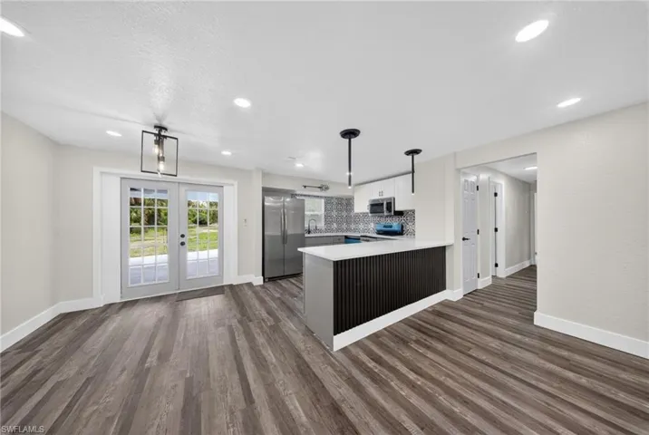 Open-concept living space featuring wood-finish flooring, recessed lighting, and a kitchen island with pendant lighting