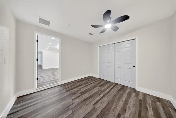 Spacious room featuring wood-finish flooring, light-toned walls, and white baseboards