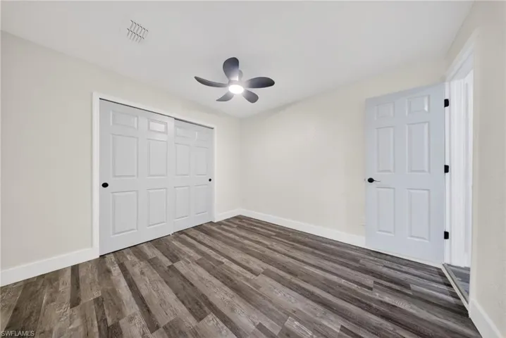 Spacious room featuring wood-finish flooring, a contemporary ceiling fan, and large sliding closet doors