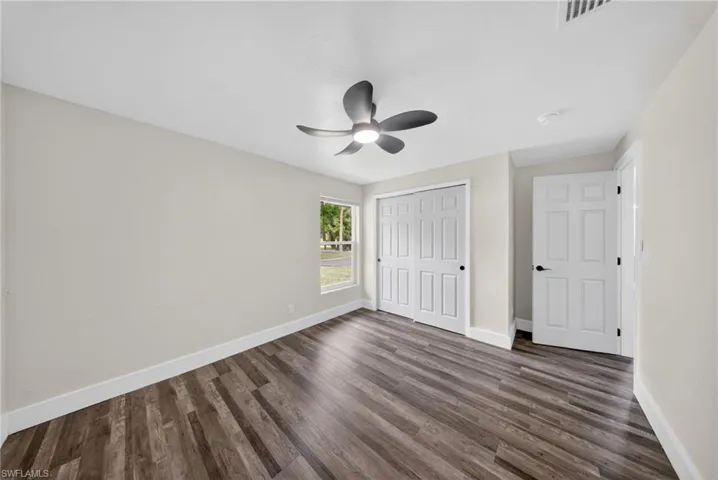 Interior room featuring wood-finish flooring, light neutral-toned walls, and a contemporary ceiling fan