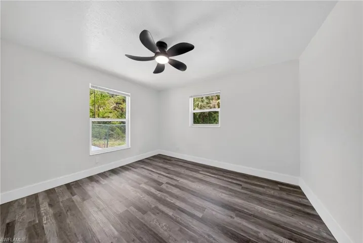 Spacious room featuring wood-finish flooring, white baseboards, and light gray walls