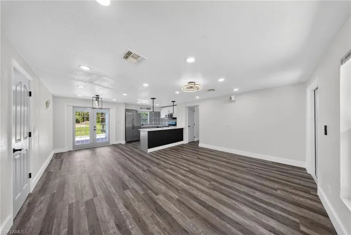 Spacious open-concept living area featuring wood-finish flooring, recessed lighting, and a contemporary ceiling fan