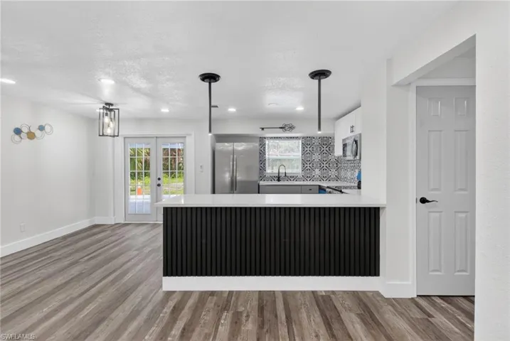 Kitchen island with a slatted black base and white countertop, featuring two pendant lights