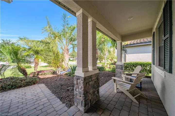 Covered front porch featuring paver flooring, stacked stone column accents, and a stucco exterior