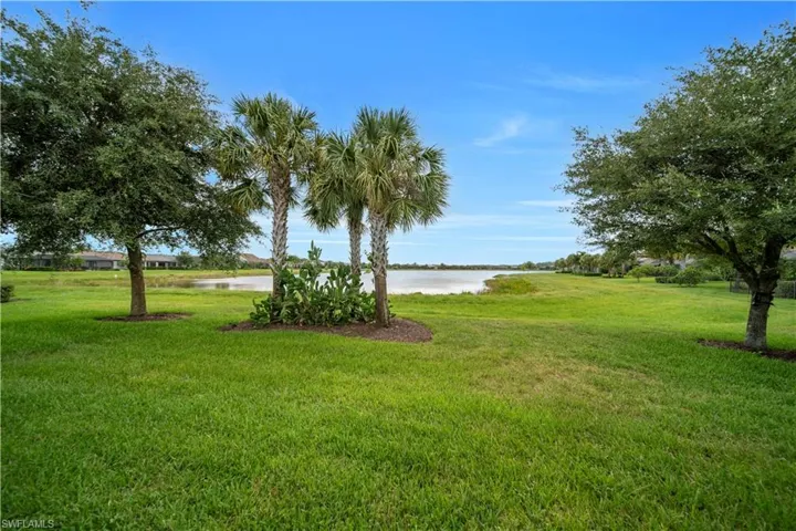 Expansive green lawn with mature trees and a tranquil lake backdrop