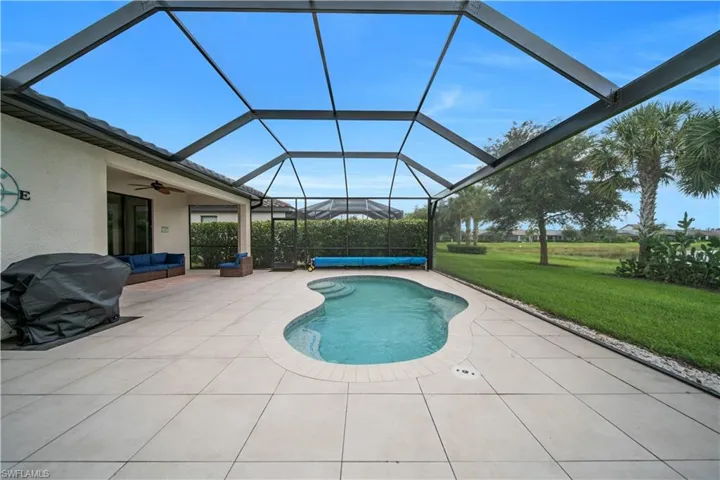 HEATED Screened-in outdoor living space featuring a free-form swimming pool with integrated spa