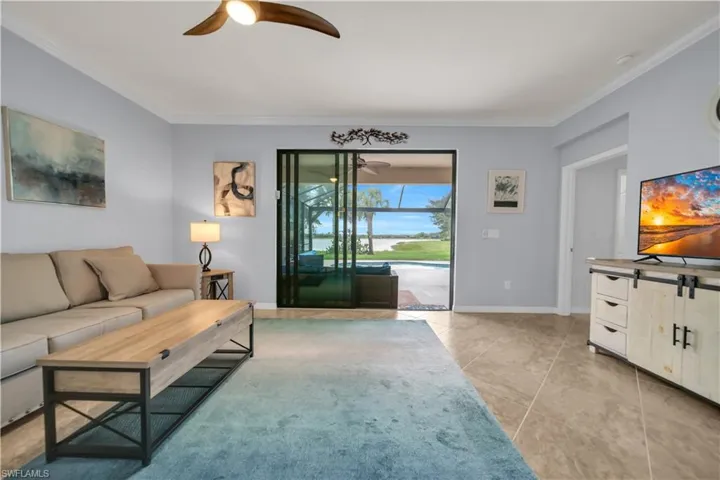Expansive sliding glass doors open to a screened lanai with pool and water frontage