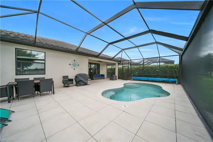 Screened lanai featuring a free-form pool with integrated spa