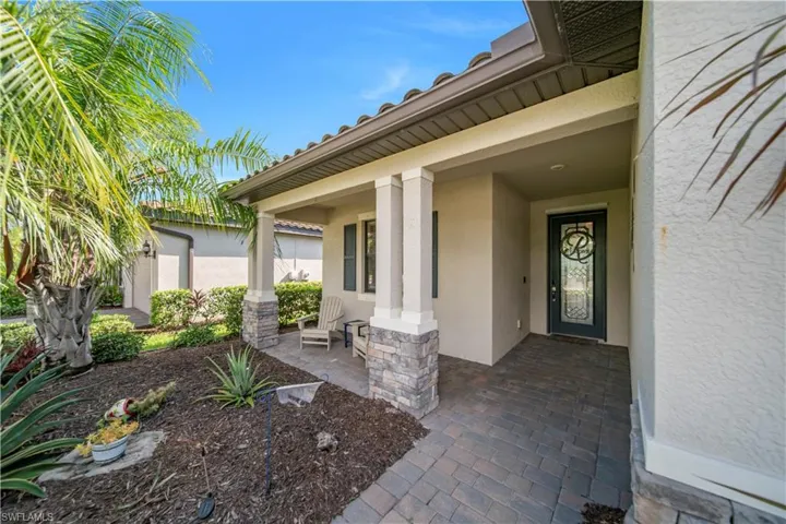 Covered entryway featuring stone-clad columns and a decorative glass front door