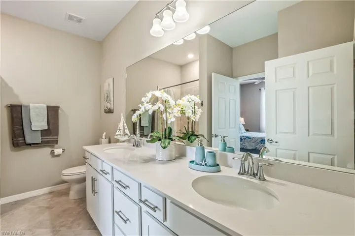 Bathroom with toilet, vanity, tile patterned floors, and ceiling fan