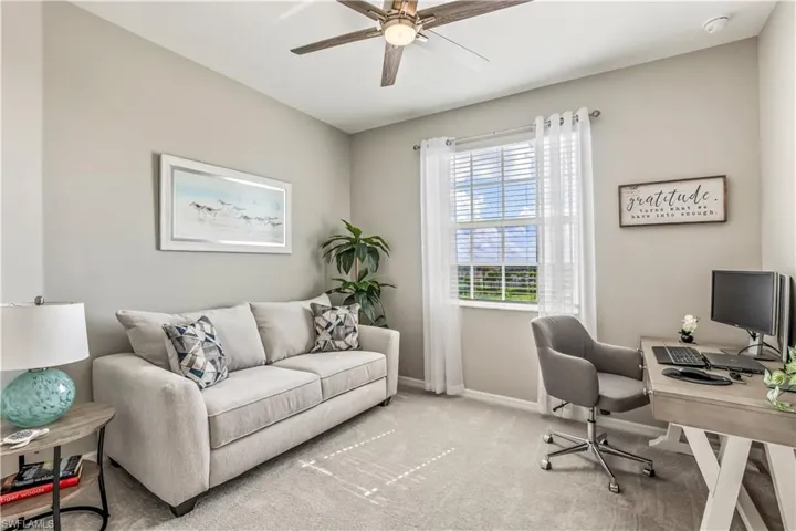 Office space with light carpet and ceiling fan