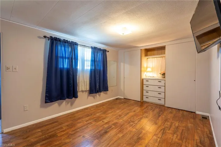 Primary bedroom with wood-style floors and closets