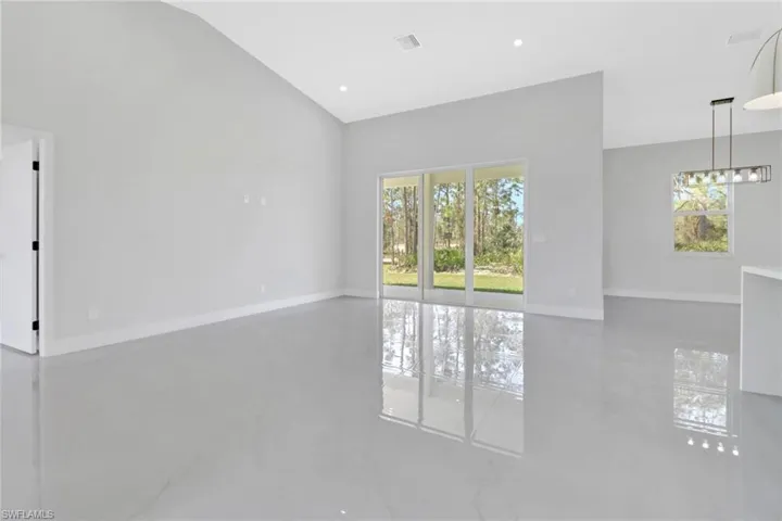 Unfurnished living room featuring a wealth of natural light and vaulted ceiling