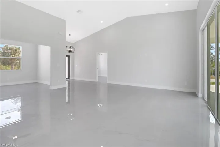 Empty room featuring high vaulted ceiling, plenty of natural light, and a notable chandelier