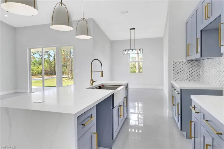 Kitchen with light tile patterned floors, an island with sink, tasteful backsplash, pendant lighting, and sink