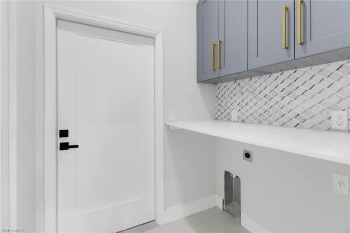 Clothes washing area with electric dryer hookup and cabinets