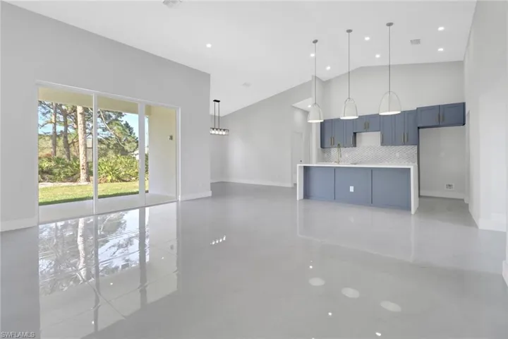 Unfurnished living room featuring high vaulted ceiling and sink