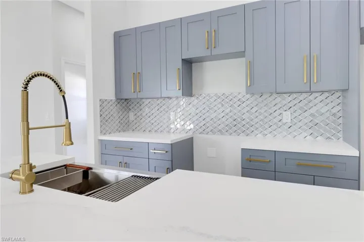 Kitchen featuring decorative backsplash, light stone counters, and sink
