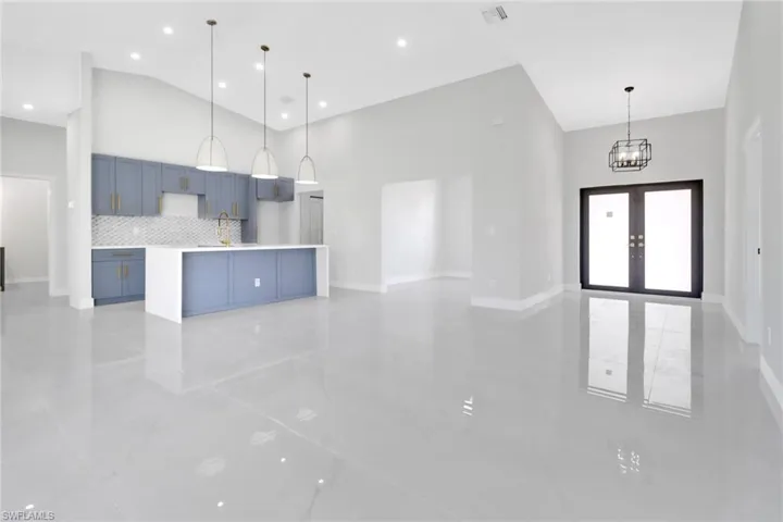 Kitchen with a spacious island, pendant lighting, decorative backsplash, a high ceiling, and blue cabinetry