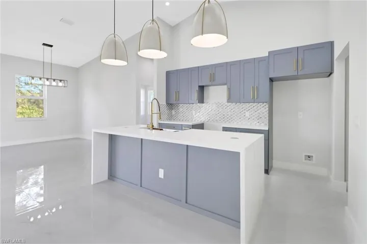 Kitchen with decorative backsplash, sink, pendant lighting, and an island with sink