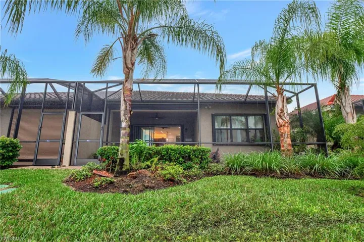 Back of property featuring a sunroom, a lanai, stucco siding, and a yard