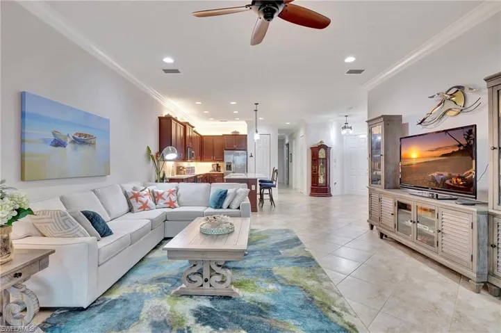 Living room with ceiling fan, crown molding, light tile patterned floors, and recessed lighting