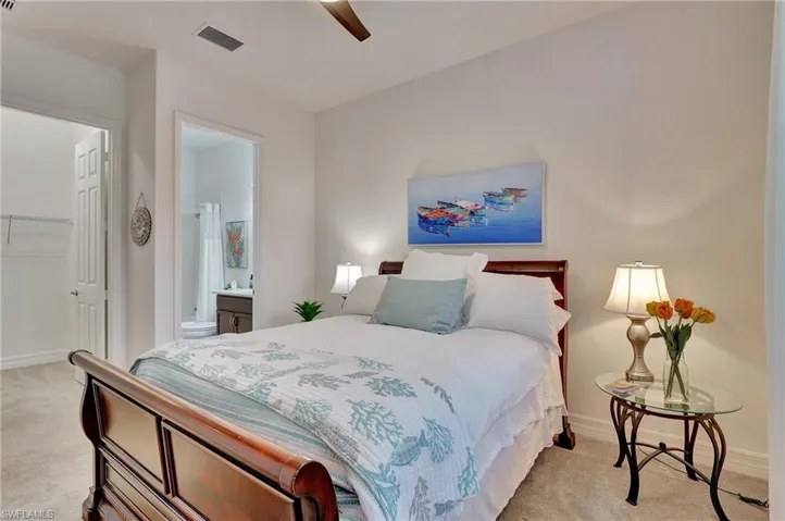 Bedroom with a spacious closet, light colored carpet, and ceiling fan