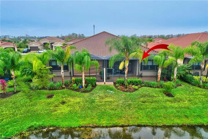 Back of house with glass enclosure, a tiled roof, a lawn, a water view, and a sunroom