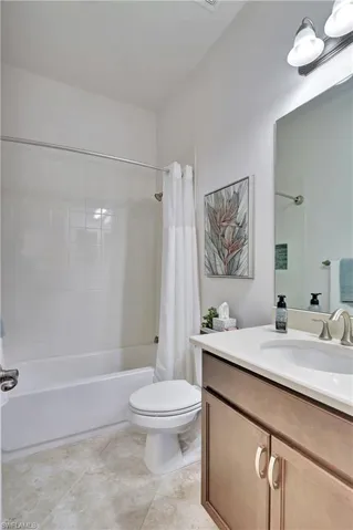 Full bath with vanity, shower / bathtub combination with curtain, and light tile patterned floors