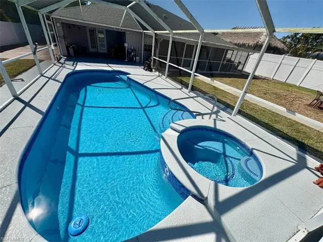 View of swimming pool with a lanai, a patio area, a fenced backyard, and a pool with connected hot tub