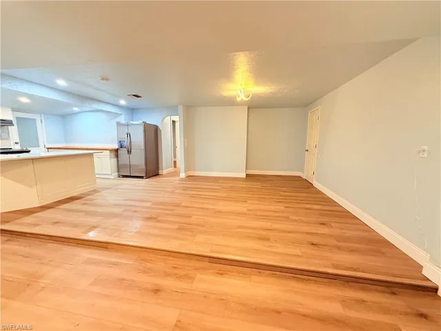 Unfurnished living room with light wood-type flooring, arched walkways, and recessed lighting