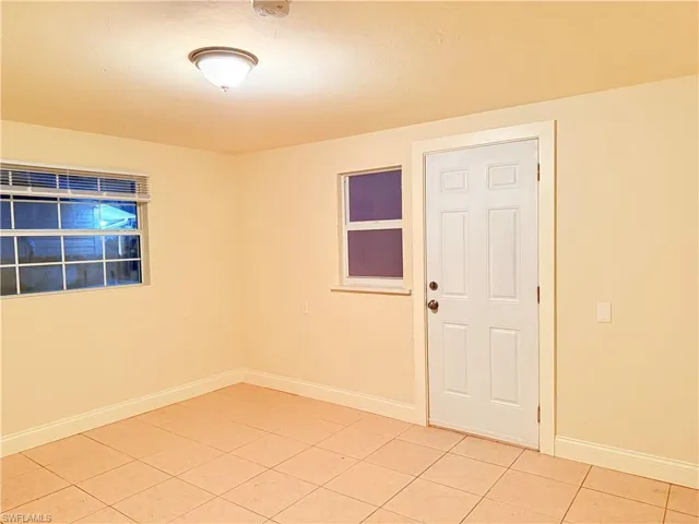 Empty room featuring light tile patterned floors and baseboards