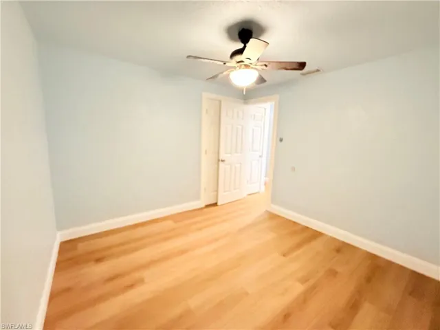 Empty room with ceiling fan and light wood finished floors