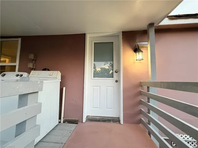 Doorway to property with separate washer and dryer and stucco siding