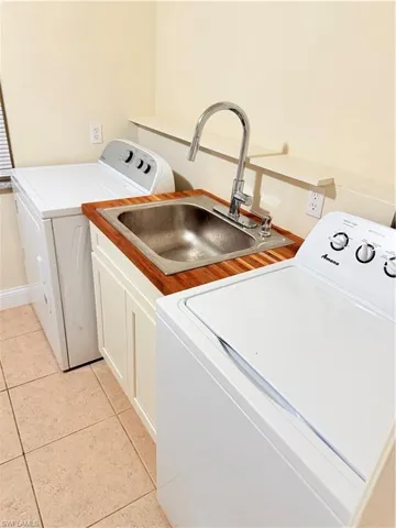 Laundry area featuring cabinet space, washer and dryer, and light tile patterned flooring