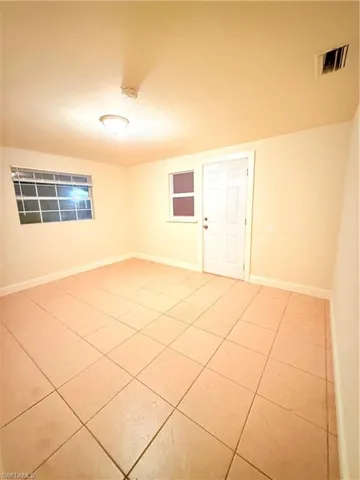 Empty room featuring light tile patterned floors and a smoke detector