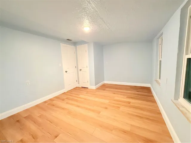 Empty room featuring a textured ceiling and light wood-style floors