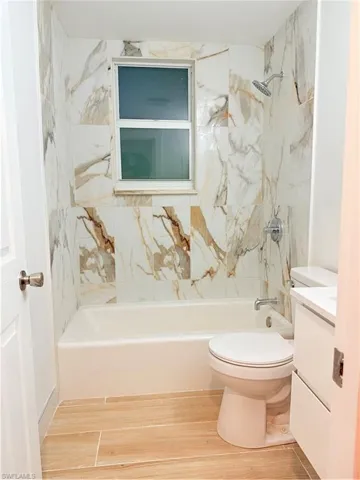 Bathroom with vanity, wood finished floors, and washtub / shower combination