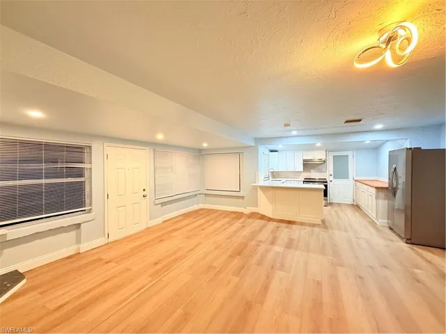 Unfurnished living room featuring light wood-style flooring, a textured ceiling, and recessed lighting