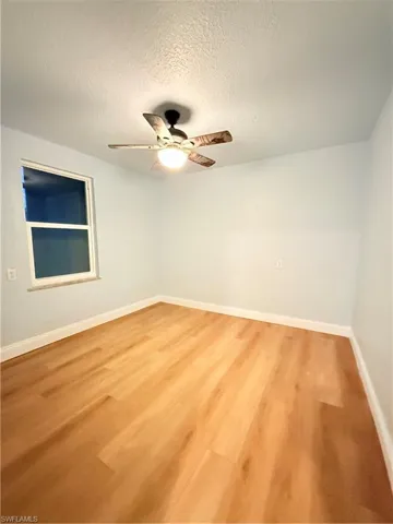 Empty room with a ceiling fan, a textured ceiling, and light wood-type flooring