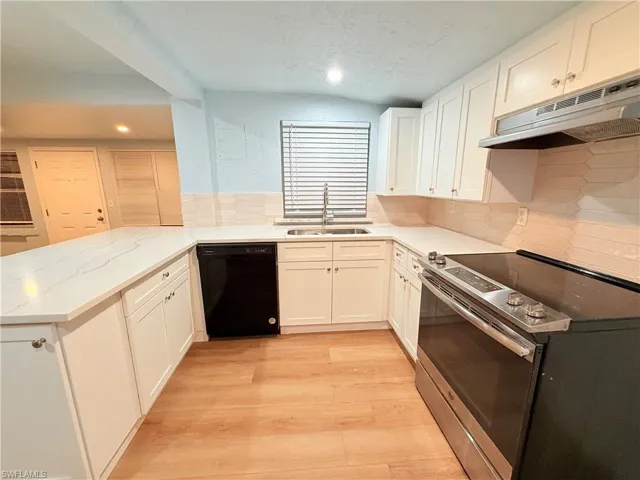 Kitchen featuring stainless steel electric range oven, black dishwasher, under cabinet range hood, recessed lighting, and a peninsula
