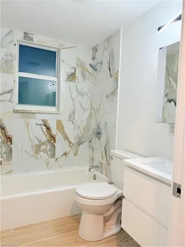 Bathroom featuring vanity,  shower combination, and wood finished floors