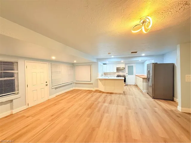 Unfurnished living room with light wood-type flooring, a textured ceiling, and recessed lighting