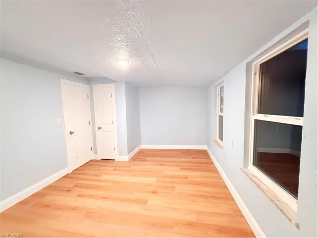 Empty room featuring light wood-type flooring and a textured ceiling